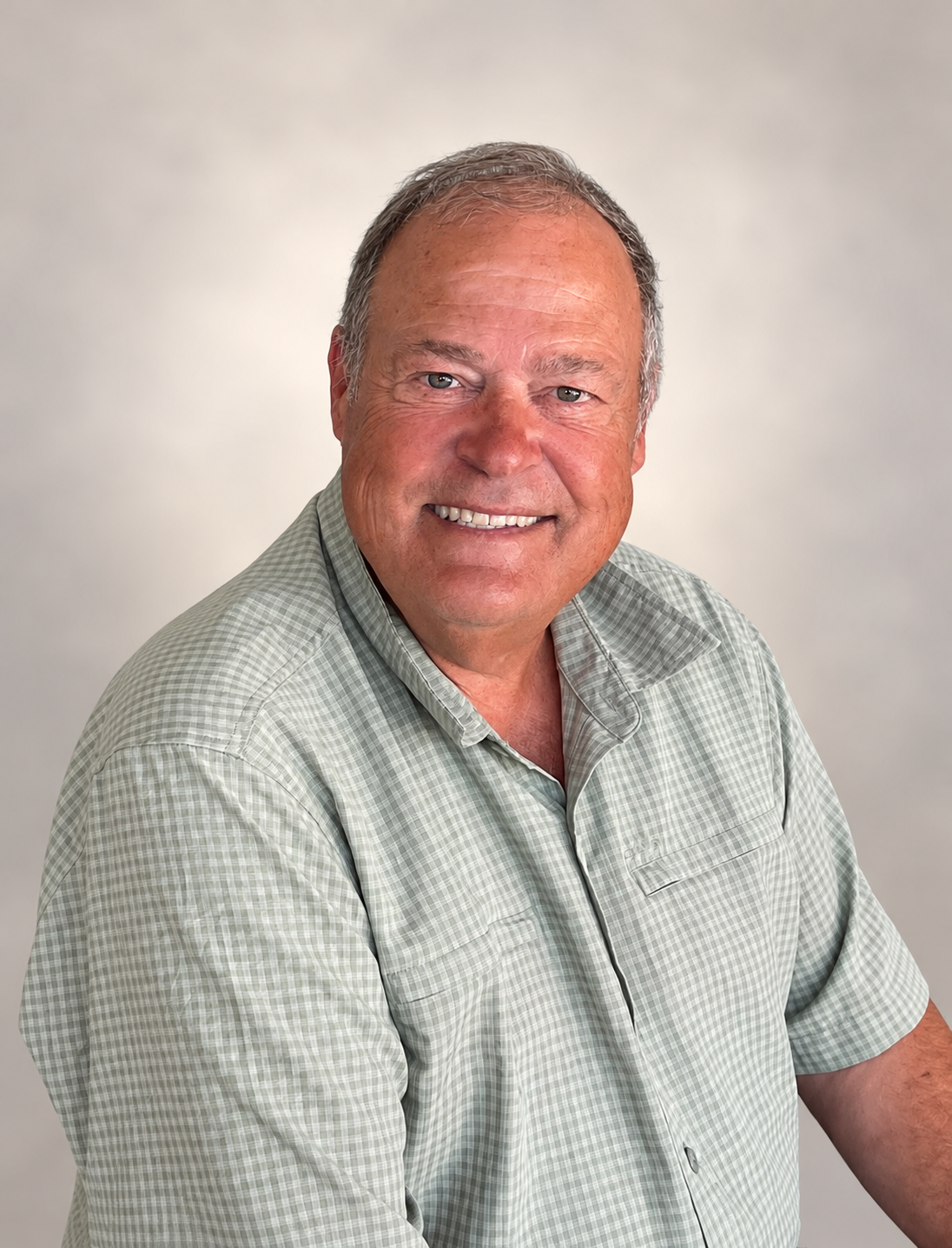 J Stucki smiling in a sage-green shirt